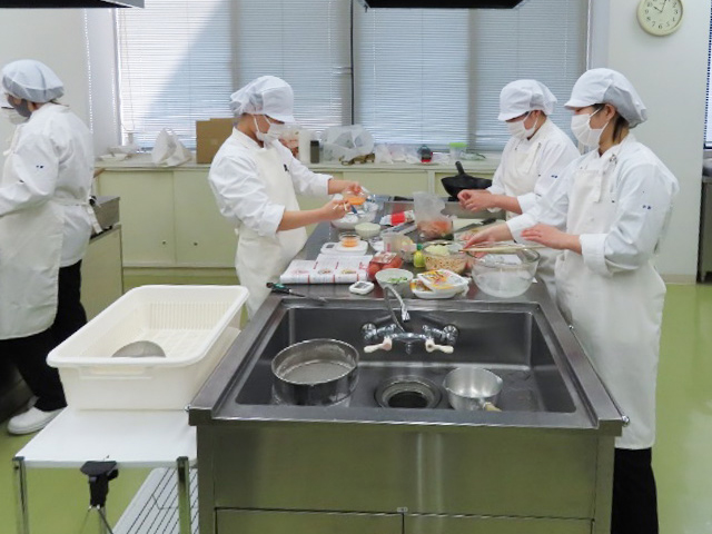 ゼミ活動でレシピ作成のための試作調理を行うAさん(写真中央)